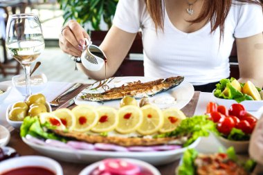 Önünde bir tabak yemekle masada oturan bir kadın görülüyor..