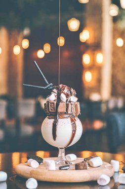 Kabarık beyaz şekerlemelerle dolu bir vazoyla süslenmiş bir masa tuhaf ve keyifli bir atmosfer yaratıyor..