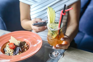 Cep telefonunu elinde tutan bir insan bir tabak yemeğin yanında durur..