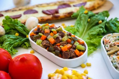 Bir masa, görsel olarak çekici bir görüntü oluşturan çeşitli yemek türleri ile doludur..