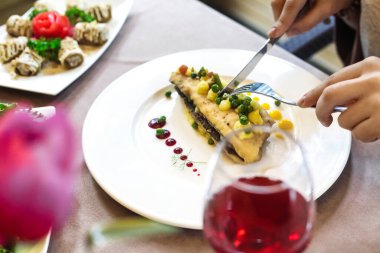 Bir insan keskin bir bıçakla bir tabak yemeği ustalıkla keser..