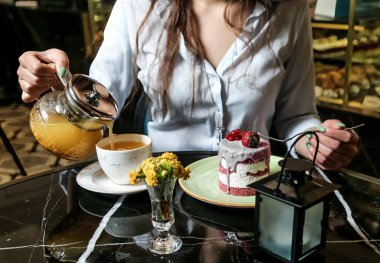 Bir kadın nazikçe çaydanlıktan sıcak çayı masanın üstündeki fincana döker..