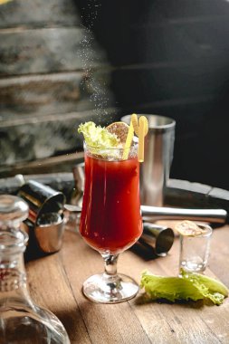 Canlı kırmızı bir sıvıyla dolu bir bardak masada oturur..