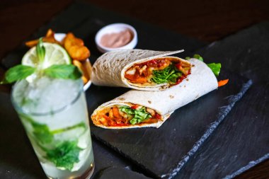 Masada ağız sulandıran bir burrito ve ferahlatıcı bir içecek sergilenir..