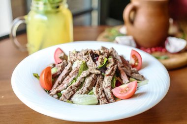 Ağız sulandıran ızgara et ve canlı sebzeler sunan beyaz bir tabak..