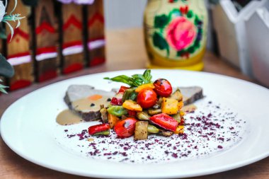 Beyaz bir tabak, bir masanın üstüne yerleştirilmiş bol miktarda yiyecek ile doludur..