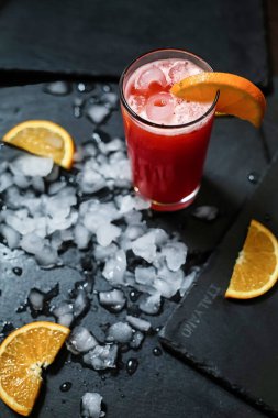 Portakal dilimleri ve buzla dolu bir içecek masaya oturur, susuzluğunu gidermeye hazır..