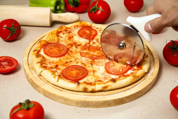 Bir insan pizzayı dilimlemek için pizza kesicisi kullanıyor..