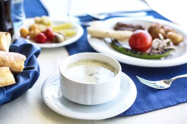 Tabaklar dolusu yemek ve tepesinde bir kase çorba olan bir masa..