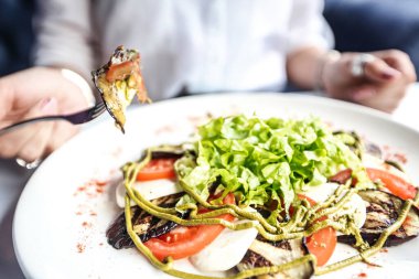 Beyaz bir tabağın üzerinde taze bir salata ve yanında da çatal var..