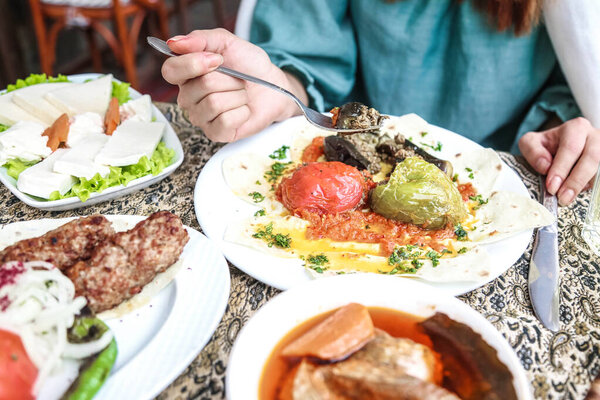 Человек сидит за столом, наполненным различными тарелками вкусной еды.
