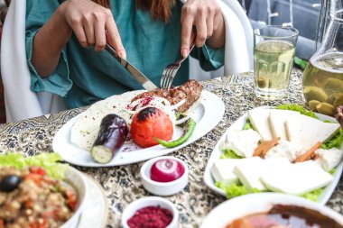 Lezzetli yemek tabaklarıyla çevrili bir masada oturan bir kadın..
