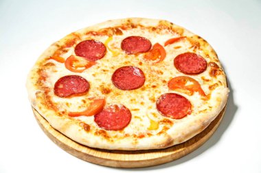 Ağız sulandıran pepperonili ve pepperonili pizzanın ahşap bir tabağa yerleştirilmiş yakın plan fotoğrafı..