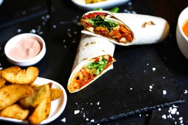 Bir dizi lezzetli yemek tabağı ve çeşitli soslarla süslenmiş siyah bir masa..