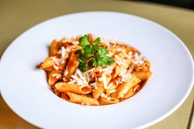 Yeni rendelenmiş parmesan peyniri ile süslenmiş ve maydanoz yapraklarıyla süslenmiş bir tabak makarna..