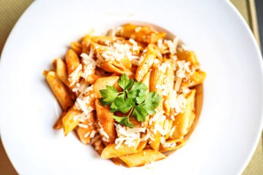 Bol miktarda rendelenmiş parmesan peyniri ve taze maydanoz yapraklarıyla süslenmiş ağız sulandıran bir tabak makarna..