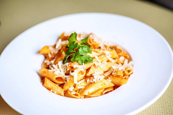 A delectable plate of pasta garnished with freshly grated Parmesan cheese and sprinkled with chopped parsley leaves.