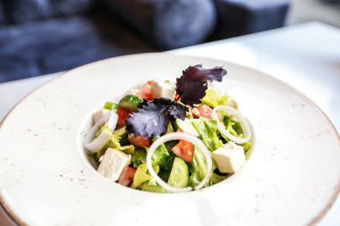 Beyaz bir tabak zarif bir şekilde masanın üzerinde sunulur, canlı ve sağlıklı bir salata sergilenir..