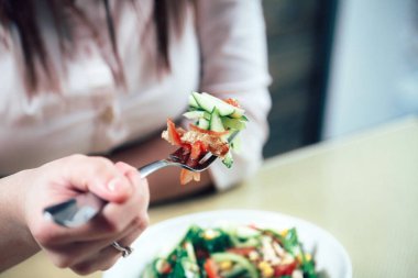 Bir kadın elinde çatal dolusu yiyecek tutuyor ve lezzetli bir yemek hazırlıyor..