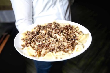 Bir insan elinde iştah açıcı yiyeceklerle dolu bir tabak tutuyor..