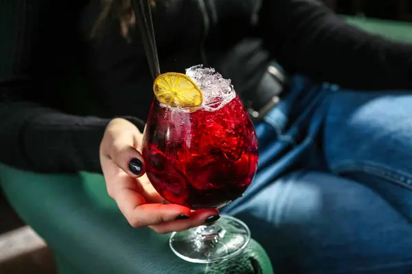 Bir kadın canlı bir sosyal etkinlikte elinde canlı kırmızı bir kokteyl tutuyor..