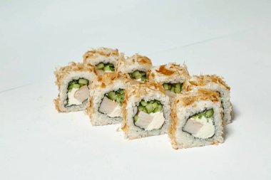 Bir grup farklı suşi yuvarlakları sade beyaz bir masa üzerinde düzgünce dizilmiş..