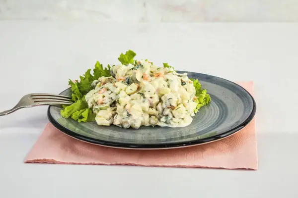 Taze marul ve çatalla süslenmiş bir tabak kremalı patates salatası..