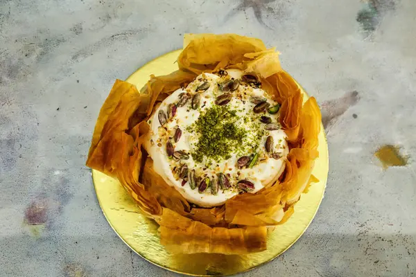 Fıstıklı ve kremalı lezzetli bir Orta Doğu tatlısının yakın çekimi, altın bir tabakta servis edilir..