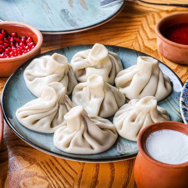 Popüler bir Gürcü yemeği olan ve ahşap bir masada servis edilen bir tabak haşlanmış Khinkali köftesi..