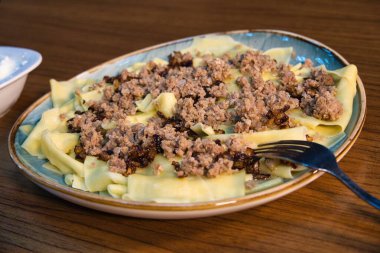 Üzerine et ve soğan konmuş bir tabak erişte..