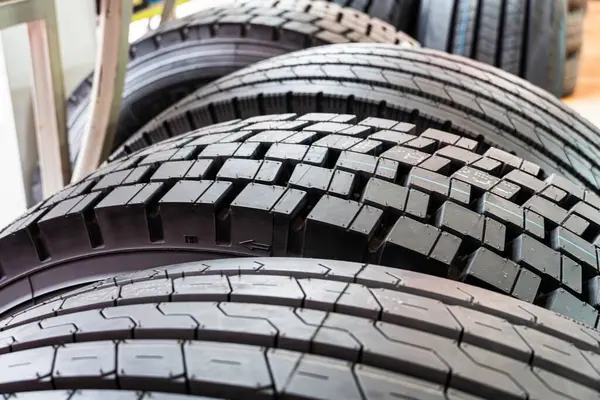 Yeni kamyon lastiklerinin yakın plan çekimi, lastik desenlerini ve sağlam inşaatı gösteriyor..