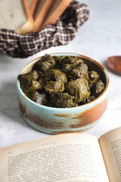 stock image A close-up shot of a bowl filled with stuffed grape leaves, showcasing their green and brown colors.