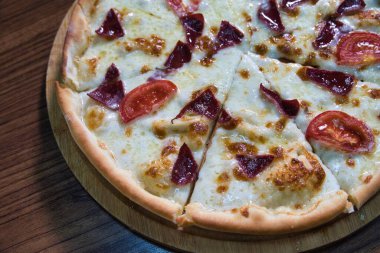 Biberli beyaz pizza ve ahşap bir tahtanın üzerinde domatesler..