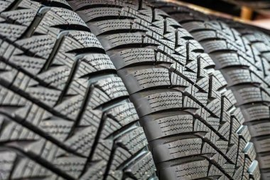 Kış lastiklerinin üst üste istiflenmiş yakın plan fotoğrafı. Karmaşık lastik desenlerini gösteriyor..
