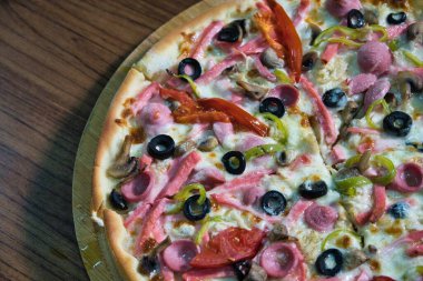 Jambonlu, mantarlı, zeytinli, biberli ve peynirli yeni pişmiş bir pizza..