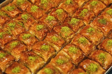 Taze pişmiş Türk baklavası tepsisinin yakın plan görüntüsü, üzerinde de doğranmış şam fıstığı var..