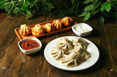 Bir tabak taze pişmiş khinkali hamur tatlısı, çeşitli soslar, kırmızı sos ve yoğurt dahil..