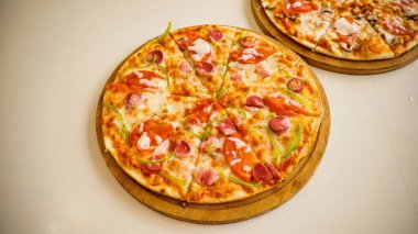 Tahtanın üzerinde sosisli, biberli ve peynirli bir pizza var..