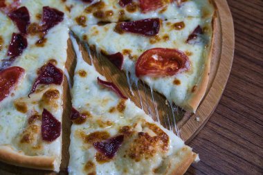 Mozarella peyniri, domates ve ahşap bir tahtanın üzerinde et ile yakın plan bir pizza..