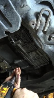 Bir tamirci araba şasisi üzerinde çalışmak için matkap kullanır. Aracın ön tarafında, arabanın şasisi üzerinde çalışıyor..