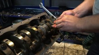 Bir tamirci, sürgüyü sıkıştırmak için İngiliz anahtarı kullanarak bir araba motoru üzerinde çalışır..