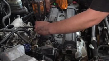 Bir tamirci, bir arabanın motorunu sıkıştırmak için matkap kullanır..
