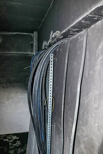 stock image A close-up shot of electrical cables hanging on a metal rack inside a fire-damaged basement.