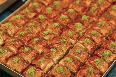 Tepsi dolusu taze fırınlanmış baklavanın yakın çekim görüntüsü. Üstünde de doğranmış şam fıstığı var..