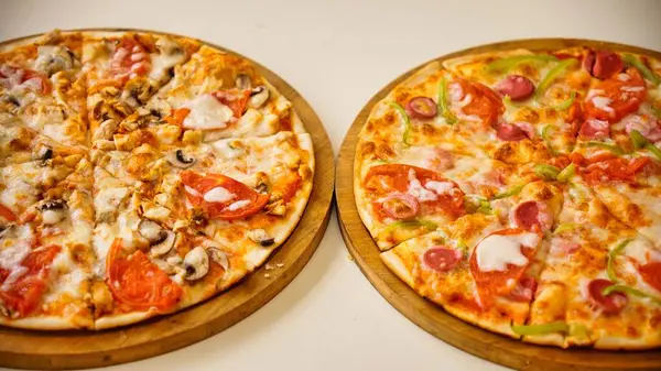 Biri tavuk ve mantarlı, diğeri biberli, sosisli ve soğanlı iki taze pizza..