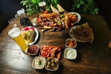 Deniz ürünleri, et, sebze ve ekmek dahil çeşitli yemeklerle dolu bir masa ve bir bardak bira..