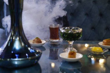 Bir nargile tabağı bir fincan çay ve bir tabak şekerle bir masanın üzerinde oturur..