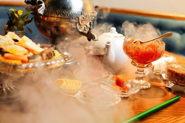 Çaydanlık, çay fincanı ve çaydanlık dolu bir masa seti. Çaydan buhar yükseliyor..