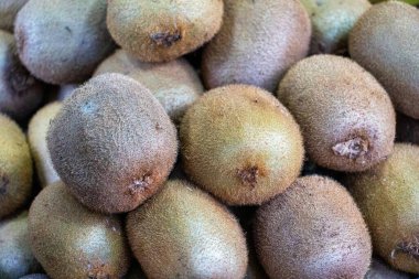 Bir market tezgahında, kahverengi tüylü derilerini sergileyen olgun kivilerin yakın plan çekimi..