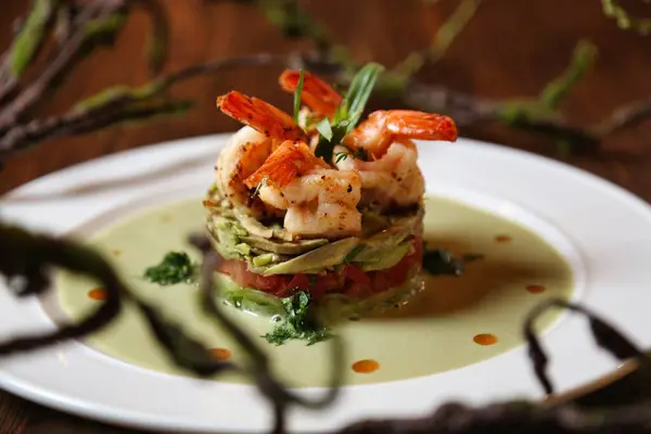 Beyaz tabakta kremalı sosla kaplı karides ve sebze salatası..